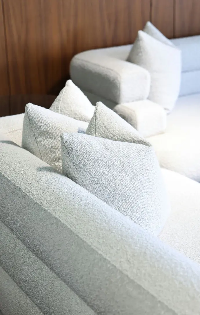 Close-up of a modern light gray textured sofa with matching throw pillows in a minimalist interior.